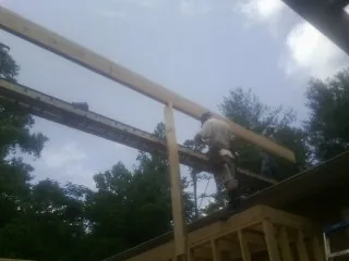 Carpenter setting a ridge beam over a new addition frame in Portland
